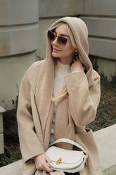 a lady in a white sweater and a long beige wool coat